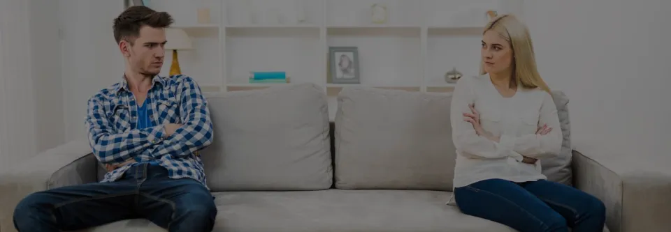 Ein Mann und eine Frau sitzen nach einem Streit abgewandt auf einem Sofa